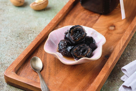 Green walnut jam in a pink bowl on a wooden tray on a green concrete background. Exotic sweets, recipes from around the world. Georgian cuisine.の写真素材
