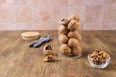 Walnuts in shell in glass jar on brown wooden background. Harvest of nuts.