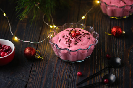 Vegan cranberry mousse on semolina in a transparent glass bowl, decorated with gratified chocolate and cranberries on a wooden background in Christmas decor. Merry Christmas. Latvian cuisineの写真素材
