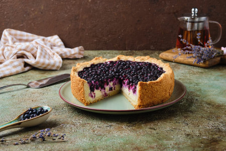 Round pie on shortcrust pastry with sweet curd filling and berries on a ceramic green plate on a green concrete background. Baking with cottage cheese. Recipes berries.の写真素材