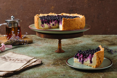 Round pie on shortcrust pastry with sweet curd filling and berries on a ceramic green plate on a green concrete background. Baking with cottage cheese. Recipes berries.の写真素材