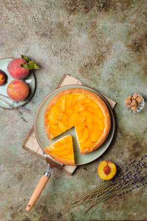 Summer pie on shortcrust pastry with custard, fresh peach slices and jelly on a plate on a textured background. Summer desserts with fresh fruits.の写真素材