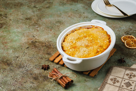 Finnish carrot casserole with rice and crispy crumble on top in white baking dish on green concrete background. Traditional food of Finns at Christmas. Vegetable, vegetarian recipes. Finnish cuisineの写真素材