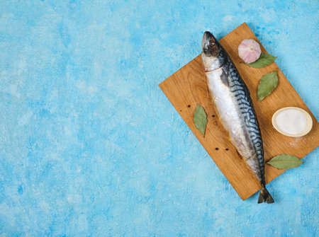 Prepared ingredients for cooking baked mackerel or other dishes from it on a wooden board on a blue concrete background. Step-by-step recipes. Fish dishesの写真素材