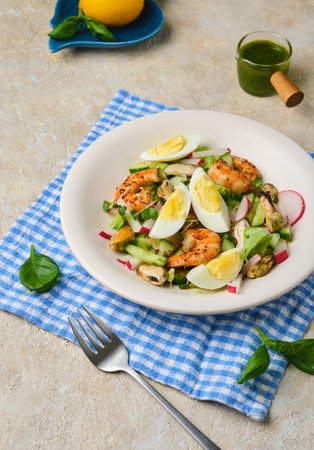 Salad of fresh cucumber, radish and eggs with seafood in a ceramic plate on a light concrete background. Salad recipes. Seafood. Healthy foodの写真素材