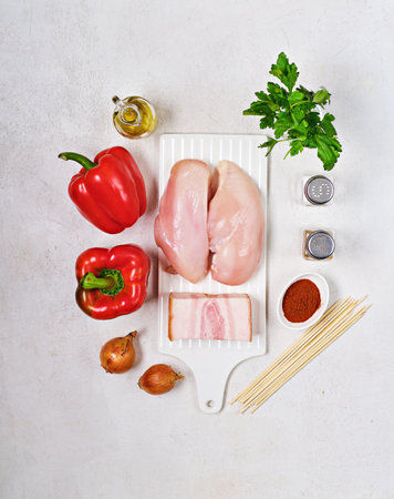 Prepared ingredients for cooking chicken with sweet pepper and onion on wooden skewers on light concrete background. Kebab, chicken on skewers. Grill season, barbecueの写真素材