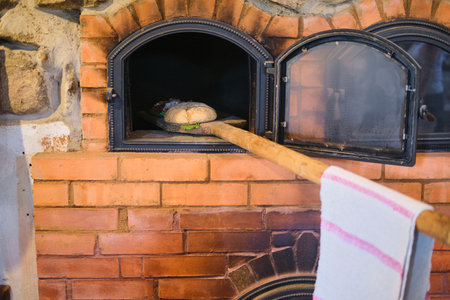 Demonstration of baking bread in a brick oven on a hearth in the ethnographic museum. Ancient crafts, skills. Bread bakingの写真素材