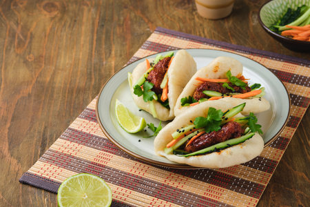 Step by step cooking of steamed bao buns stuffed with chicken, fresh cucumber and carrot on a wooden background. Ready bao buns stuffed with chicken and vegetables on a plate. Step by step recipesの写真素材