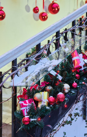 Christmas decoration, snow-covered red balls and fir branches with garlands on the parapets of the stairs outside. Merry Christmasの写真素材