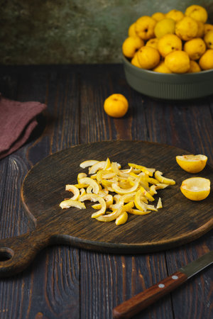 Japanese quince or chaenomeles fruits, peeled of seeds and sliced, on a brown board against a wooden background. The fruits are from edible shrubsの写真素材