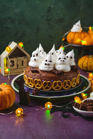 Halloween sweets, pumpkin cream cake decoration with meringue ghosts on a purple background. Happy Halloween. Trick or treat. Halloween party treats.の写真素材