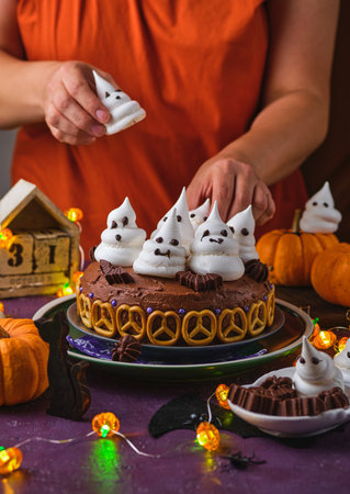 Halloween sweets, pumpkin cream cake decoration with meringue ghosts on a purple background. Happy Halloween. Trick or treat. Halloween party treats.の写真素材