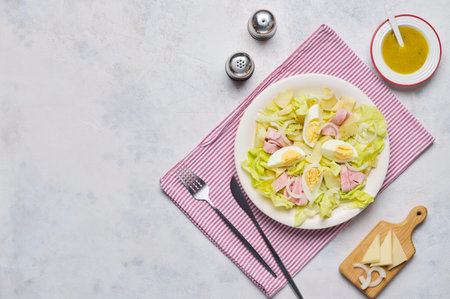 Parisian salad of lettuce, boiled potatoes, ham, and hard-boiled eggs in a light-colored plate against a gray concrete background. Salad as a main course. French cuisineの写真素材