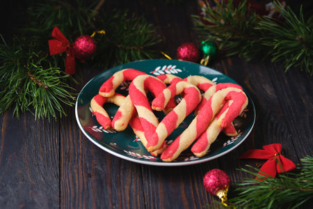 Christmas candy cane shortbread cookies on a green plate with Christmas decor against a dark wooden background. Merry Christmas. Traditional Christmas treats.の写真素材