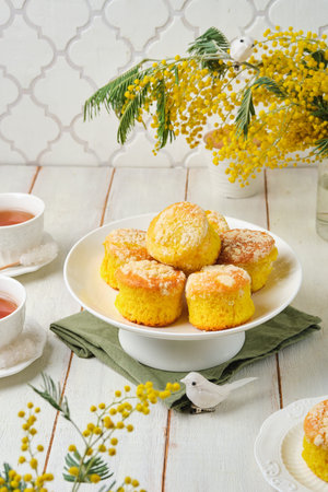Mimosa cupcakes on a white cake stand against a wooden white background. Spring celebration. Happy...