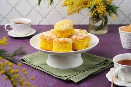 Mimosa cupcakes on a white cake stand against a purple concrete background.