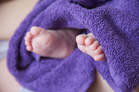 Baby foot folded in purple towelの写真素材