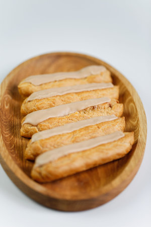 Eclairs on white background with a wooden plate