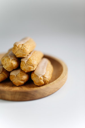Eclairs on white background with a wooden plateの写真素材