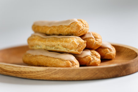 Eclairs on white background with a wooden plateの写真素材