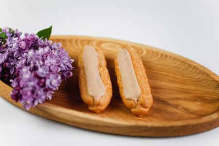 Eclairs on white background with a wooden plateの写真素材