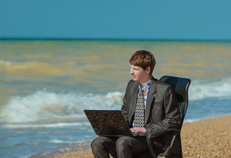 man with laptop sitting in an office chair outdoorsの写真素材