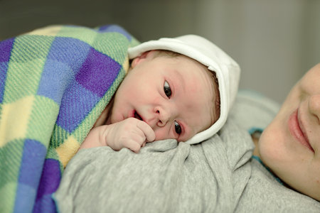 happy woman after the birth of a newborn baby on a functional bedの写真素材