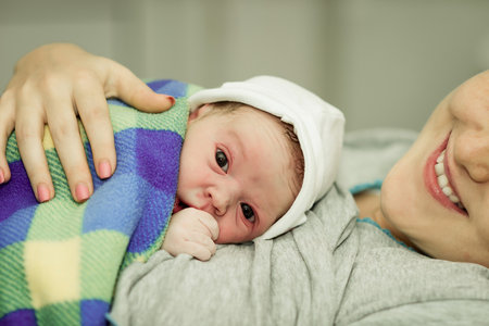 happy woman after the birth of a newborn baby on a functional bedの写真素材