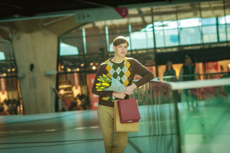 young man with shopping bags, man in shop with bags and a bouquet of tulipsの写真素材