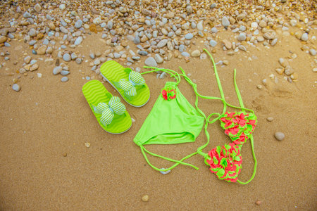 Female swimsuit and flip flops on the beach, top viewの写真素材