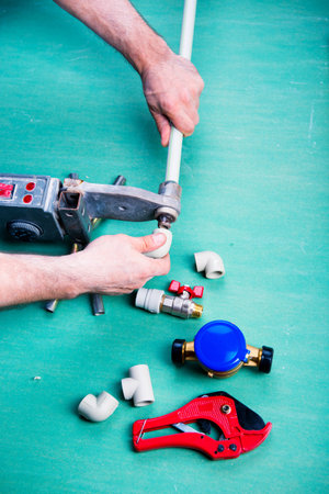 Soldering iron for polypropylene plumbing pipes. The hands of the plumber are holding the pipeline...