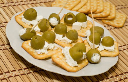 Crackers with olives and cheese feta on white plateの写真素材