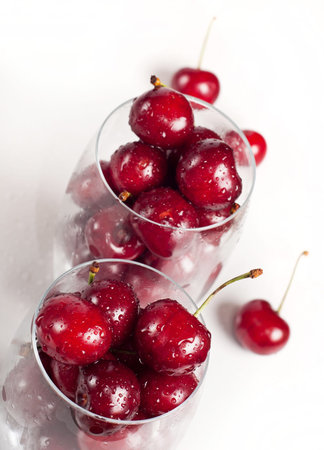 sweet cherries in glasses on white