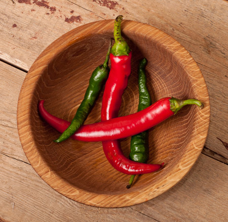 Red and green and pepper on wooden dishの写真素材