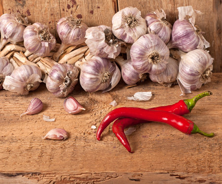 Garlic and two red pepper on wooden tableの写真素材