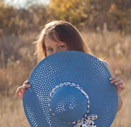 Young beautiful woman and big blue hat on natureの写真素材