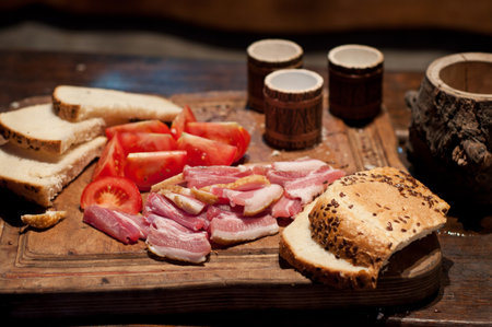Bacon, tomato, bread and moonshine on the tableの写真素材