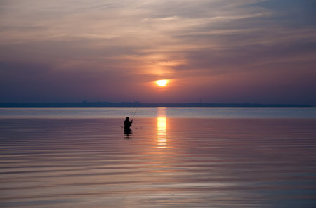 Silhouette of fishermen on the beautiful sunset backgroundの写真素材