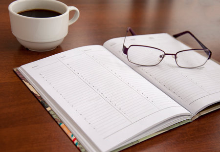 blank checklist on wooden table With coffee and glassesの写真素材