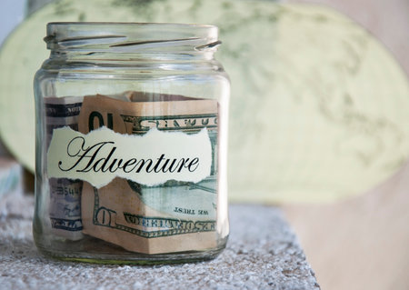 A glass jar with money put aside for a holiday with the inscriptionの写真素材
