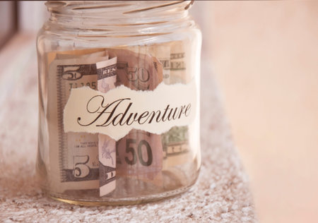 A glass jar with money put aside for a holiday with the inscription
