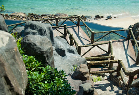 Stairs from the mountain slope to the sandy beach by the sea.の写真素材