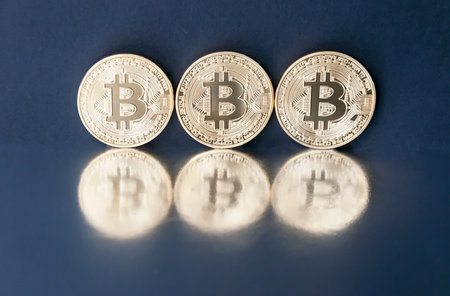 Three coins of gold bitcoin are reflected in the mirror surface. The concept of virtual business.の写真素材