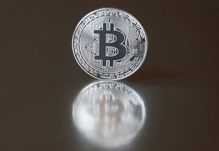 The silver coin bitcoin lies or stands on the edge on a dark mirror background, reflected. The concept of crypto currencies.の写真素材