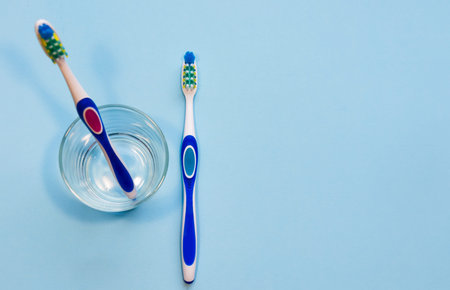 Two toothbrushes in a glass. A man's hand takes one toothbrush.