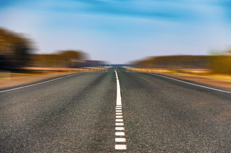 The picturesque landscape and the Sunrise over the road. Asphalt road with marking. With the blur...