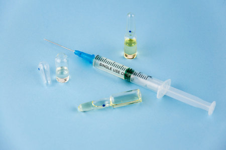 Syringe and small ampoules with medicine on a blue background