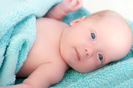 A beautiful newborn girl lies wrapped in a towel after bathingの写真素材