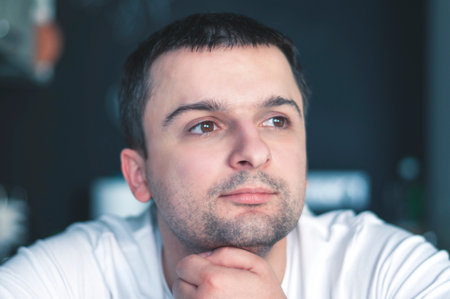 A young, attractive man in the morning in the kitchen is drinking coffee, smilingの写真素材