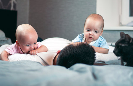 Young father with his newborn twins lying in bed. Selective focusの写真素材